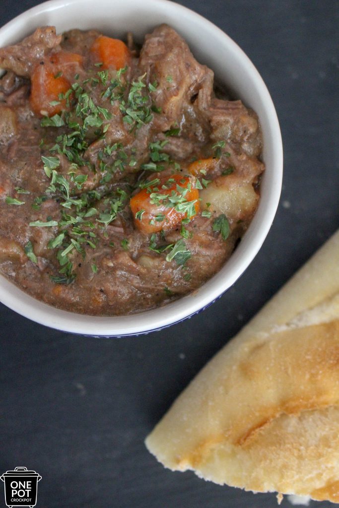 delicious bowl of hearty beef stew with bread on table