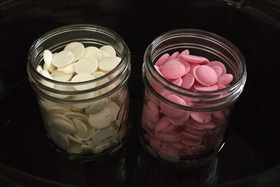 2 mason jars, one with white candy melts and one with pink.