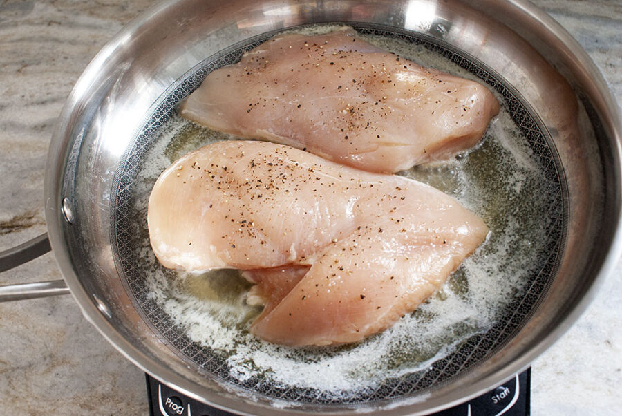 Raw chicken being cooked in a skillet