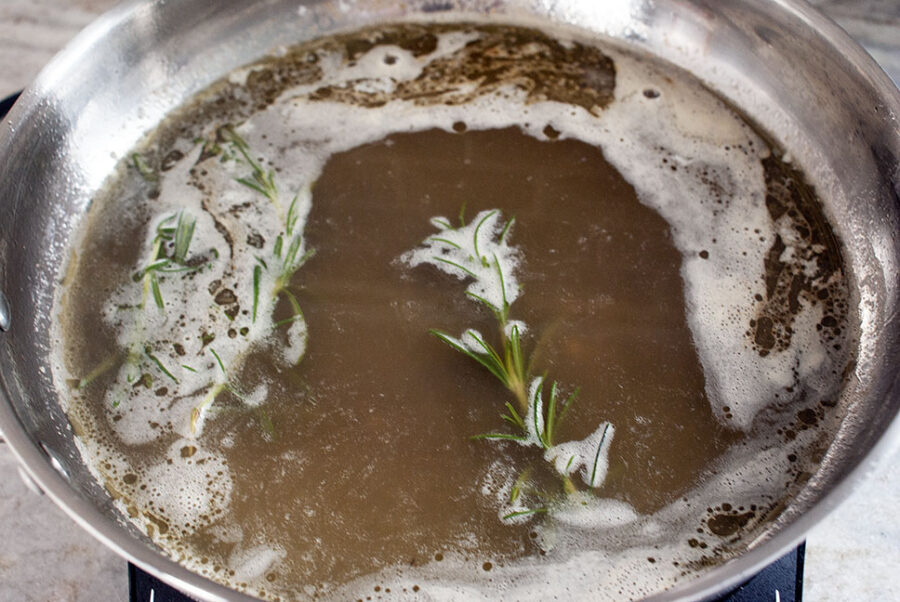 Rosemary sprig cooking in chicken broth