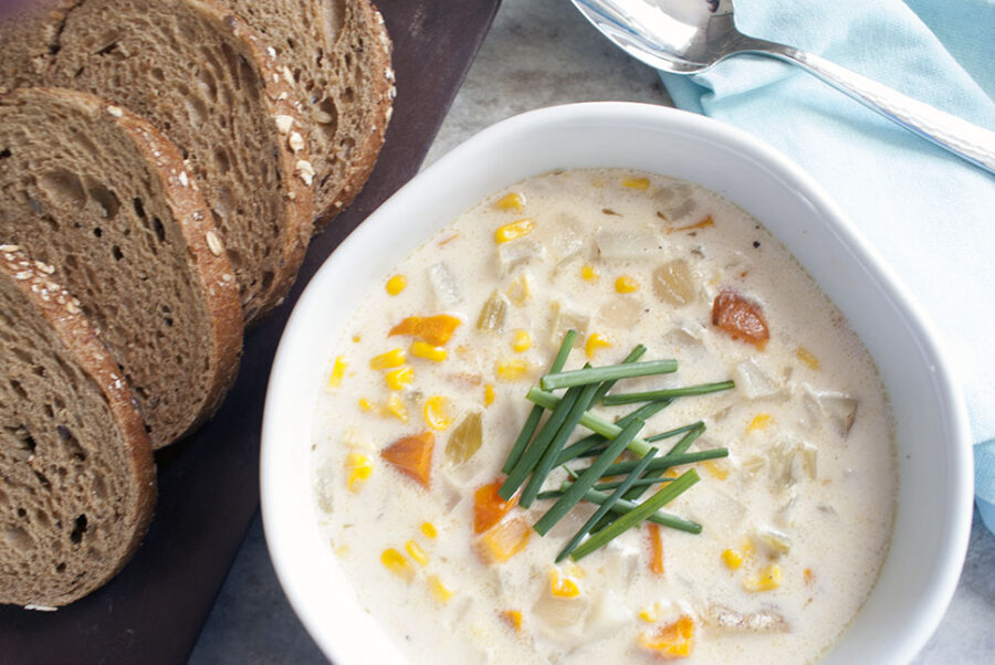 a bowl of creamy corn chowder with slices wheat bread