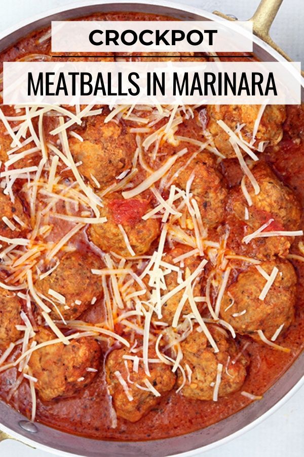 Italian meatballs topped with shredded cheese cooking in the crock pot.